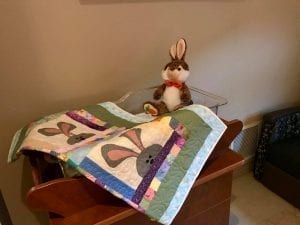 Bassinet with quilt and stuffed toy bunny rabbit